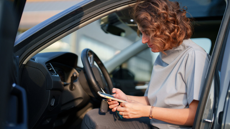 A woman using her smartphone in the seat of a car.
