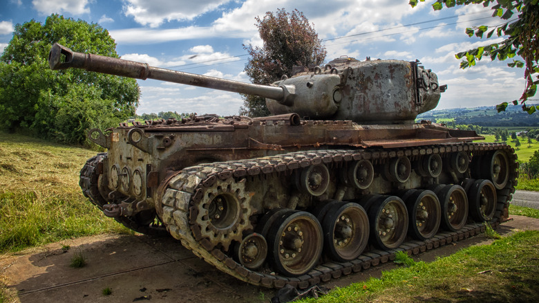 A sherman tank that was powered by the Ford GAA V8 engine abandoned off road under clear skies
