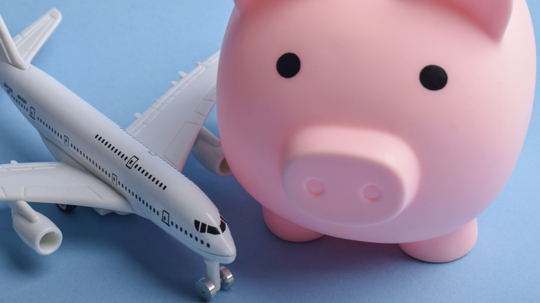A toy airplane sitting next to a large pink piggy bank