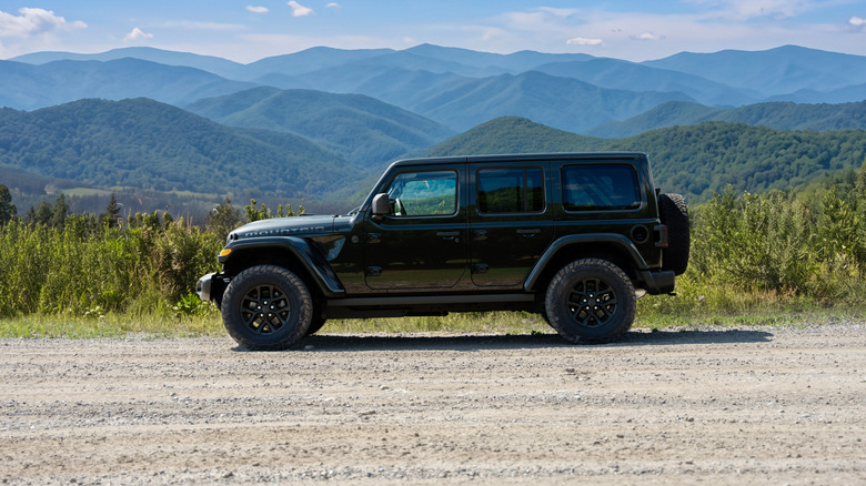 Side view of Jeep Wrangler parked on dirt road in mountainous setting