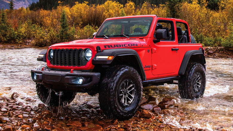 Front 3/4 view of Jeep Wrangler two-door crossing a stream in outdoor setting