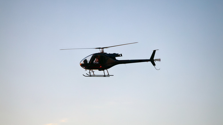 A small helicopter flying through the air against clear skies