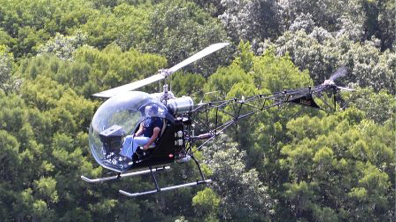 A Safari 400 helicopter flying over a forest