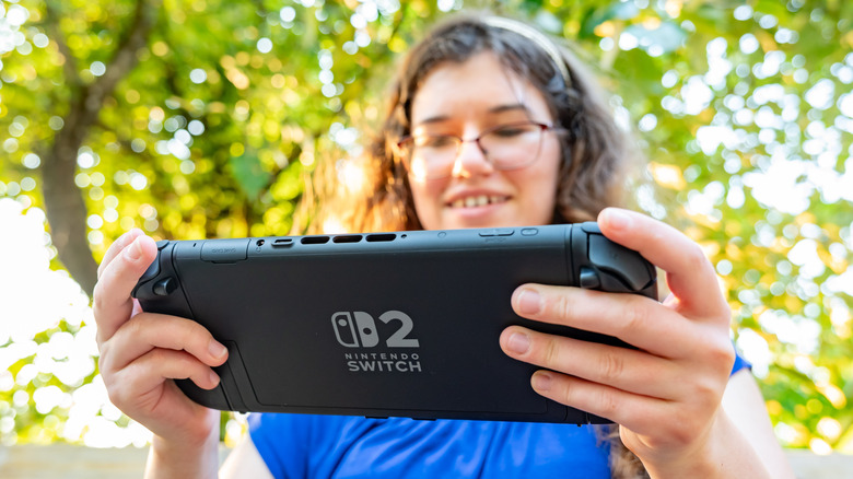 man holding Nintendo Switch 2 outside while playing