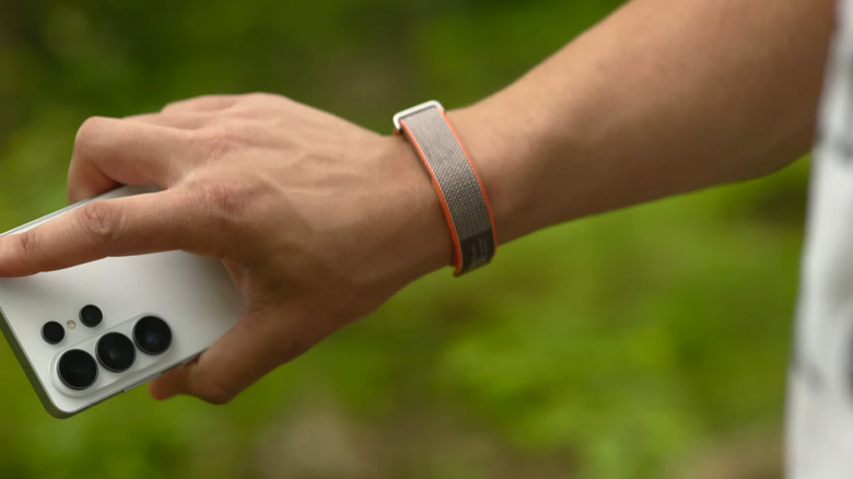 Man wearing FitBit tracker and holding a white smartphone