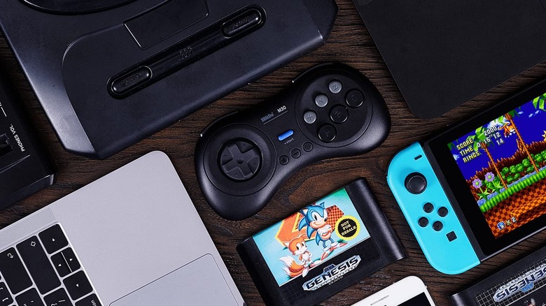 An 8BitDo M30 controller with a Switch, Megadrive, Macbook, and a Sonic Sega Genesis cartridge.