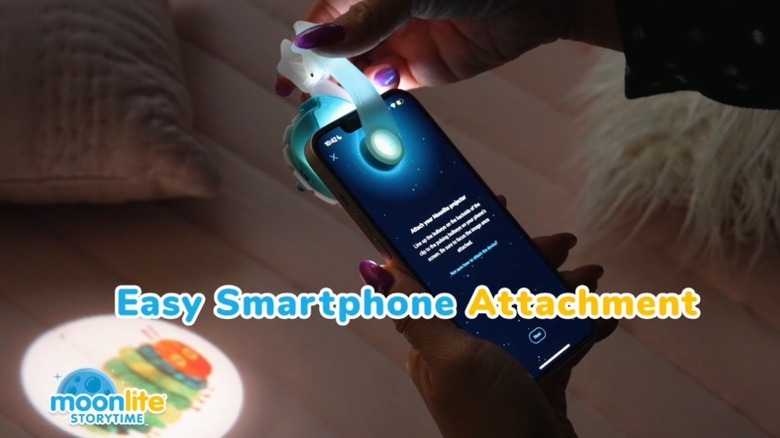A woman is attaching the Moonlight Storytime Projector to her iphone