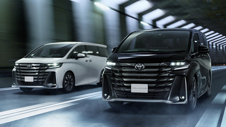 White and black Toyota Vellfires driving in a tunnel