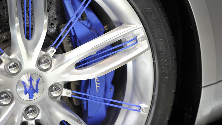 The Maserati trident in blue on the center of a wheel on a silver vehicle