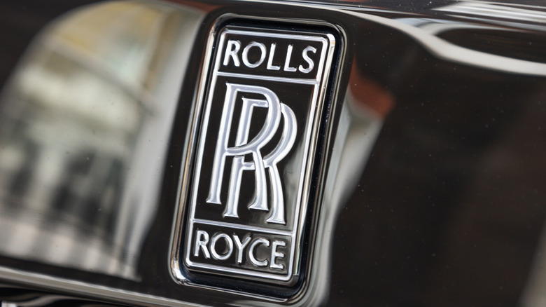 Close-up of a silver Rolls-Royce logo on a black vehicle