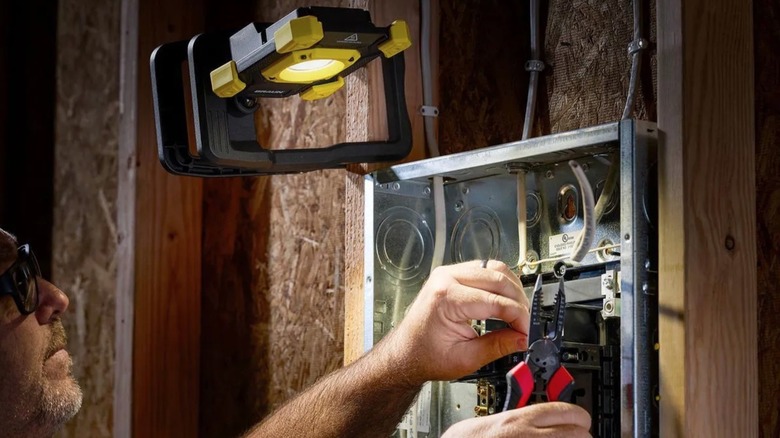 Person using Bauer clamp light to work in a basement