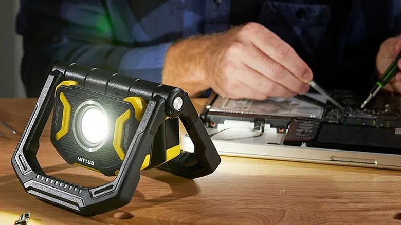 Using a foldable multidirectional work light to repair a circuit board.