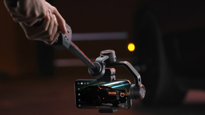 A person filming a car with the Hohem iSteady M7 AI Tracking Smartphone Gimbal.