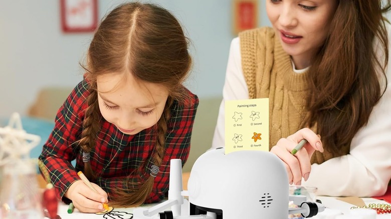 A parent and child using a drawing robot