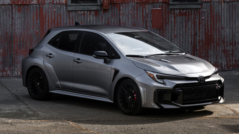 A gray Toyota GR Corolla parked in front of an industrial building.