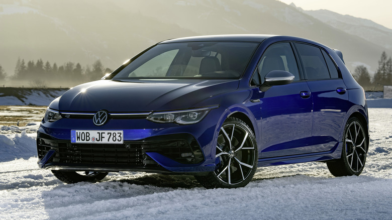 A blue Volkswagen Golf R parked in snowy conditions during a sunset.