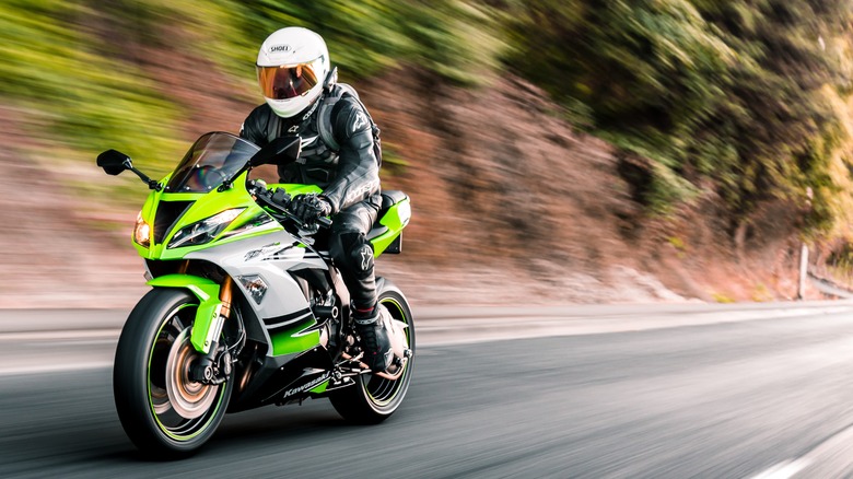 A rider on a green Kawasaki superbike. 