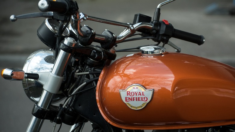 Closeup of Royal enfield logo on the orange tank of motorbike