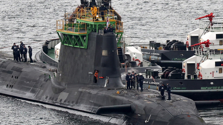 HMS Artful, an Astute Class submarine docked at HMS Clyde, a UK naval base, being tended to by a maintenance crew