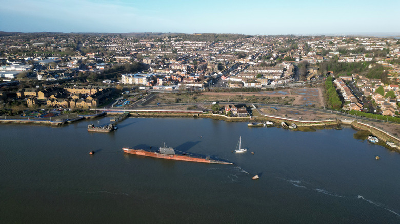 A drone picture of a submarine moored next to a riverine port in the United Kingdom