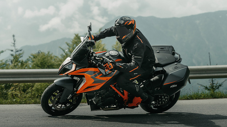 A black and orange KTM 1290 Super Duke GT being driven through mountains