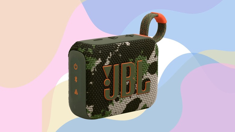 A JBL Go 4 speaker in Squad color against a multicolored pastel background.