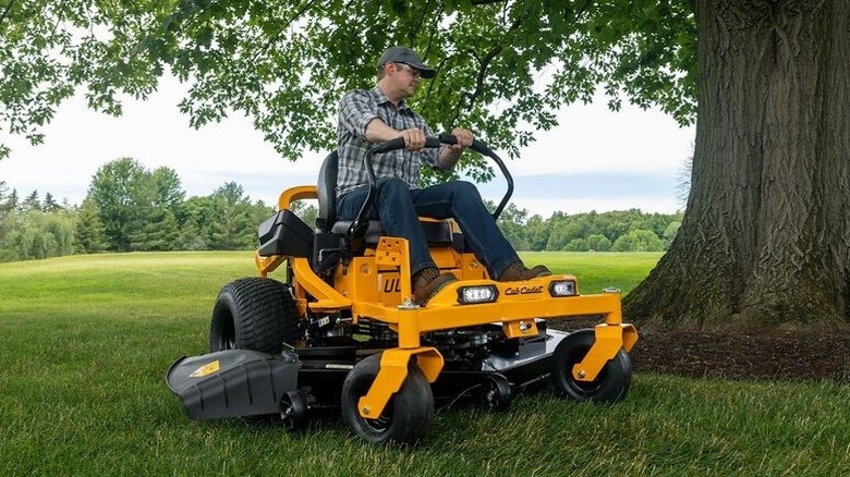 Person riding a Cub Cadet Ultimate ZT1 60 in a large field next to a tree