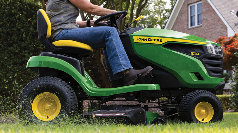 Person riding a John Deere S120 Lawn Tractor on a lawn