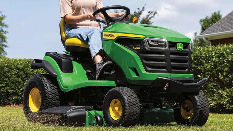 Person riding a John Deere S240 Lawn Tractor riding mower on a lawn