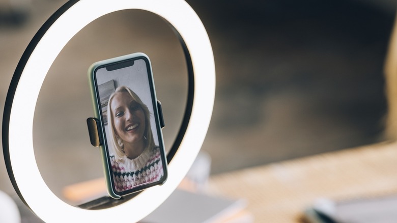 woman smiling on a phone with a ring light