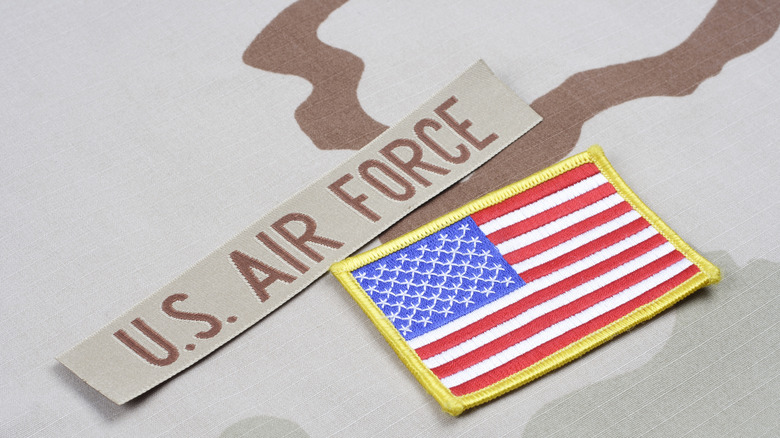 A U.S. Air Force patch with an American flag patch against a dessert camouflage background
