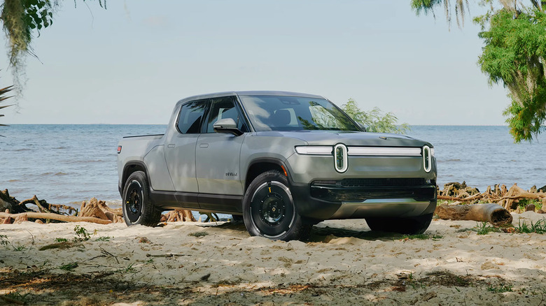 A gray 2025 Rivian R1T parjed on a beach