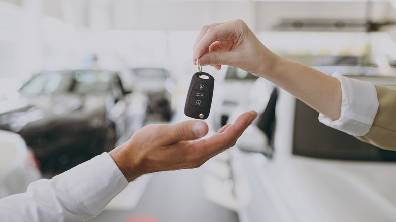 A car dealer handing a key fob to a customer