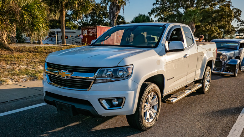 Front 3/4 view of white second-gen Chevy Colorado pickup truck on street.