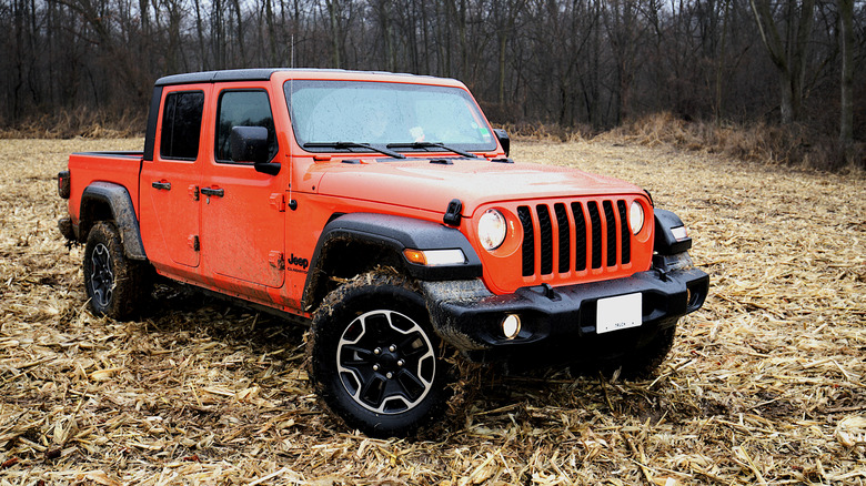 Front 3/4 view of orange Jeep Gladiator parked in field.