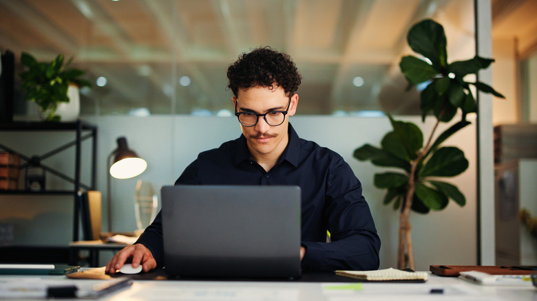 Person looking studiously at their laptop and using a mouse.