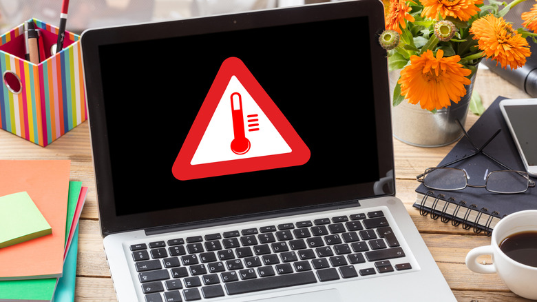 Laptop with a temperature warning displayed on the screen.