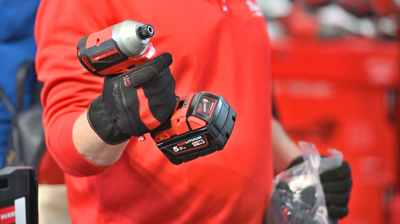man holding milwaukee drill with battery