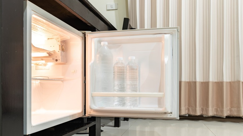 Opened mini fridge seen from the side