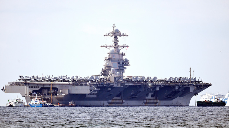 The USS Gerald R. Ford aircraft carrier pictured at the horizon line of sea and sky.