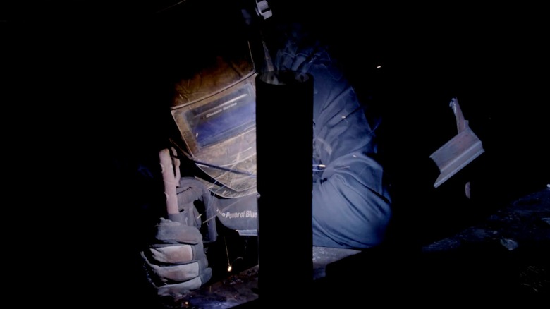 A Navy Hull Maintenance Technician welding a part aboard a vessel.