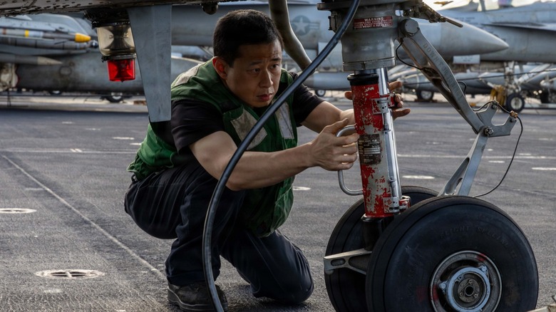 A sailor working on the landing gear of an MH-60R Sea Hawk Helicopter aboard the USS Abraham Lincoln.