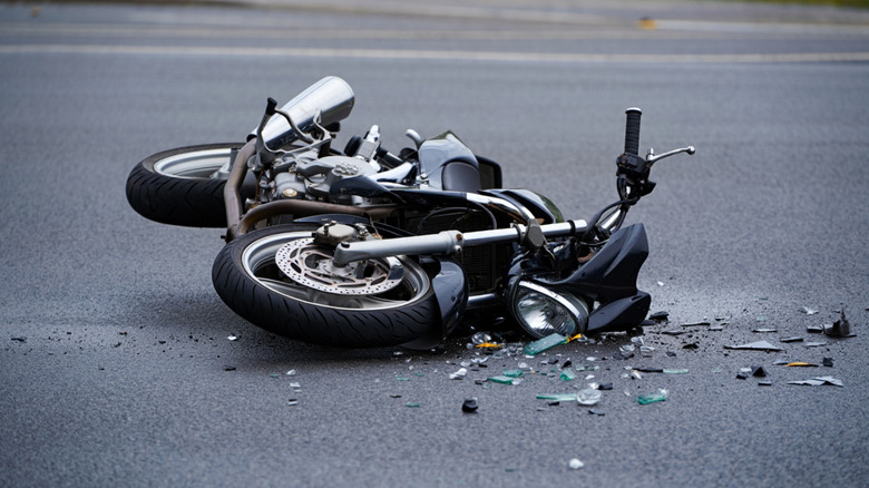 Black motorcycle laying in road post-accident