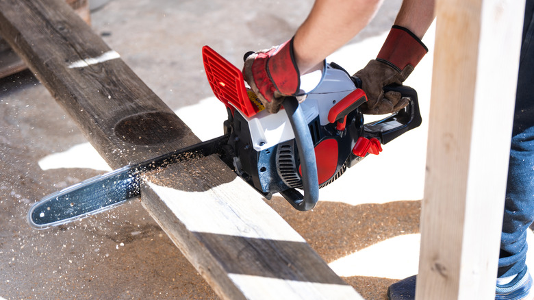 A manual worker cutting wood with a chainsaw
