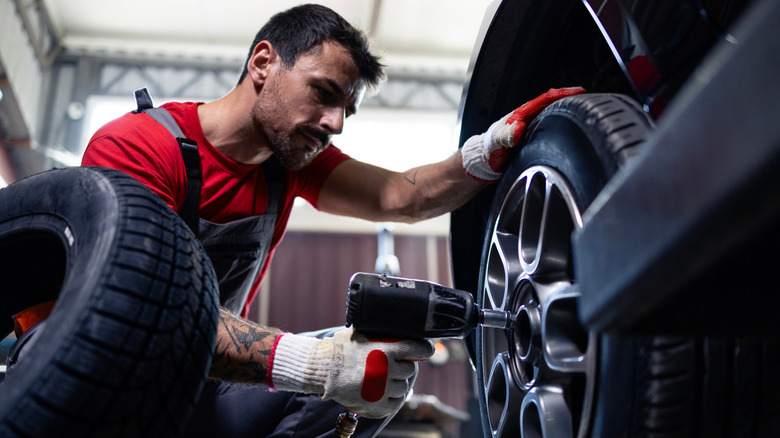 A mechanic removing a wheel from a vehicle using an impact wrench