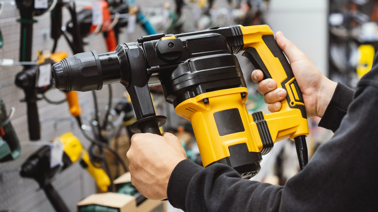 A person holding a yellow heavy-duty rotary hammer in a store