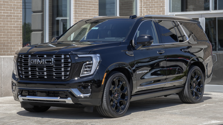 A black 2026 GMC Yukon outside a dealership, front 3/4 view