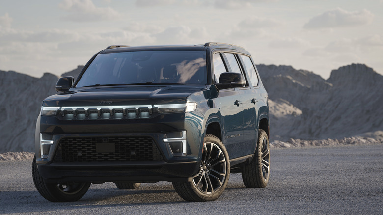 Front view of  dark blue Jeep Grand Wagoneer on gravel pad in mountains