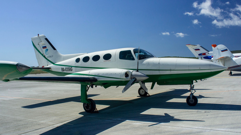 White and green Cessna 402B on tarmac under blue sky