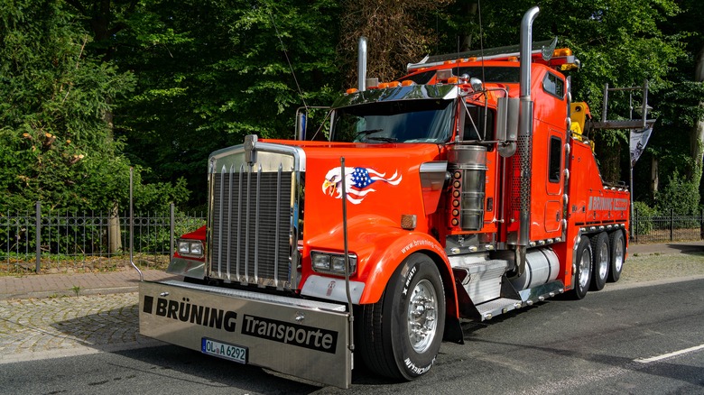 A bright-red Kenworth W900L in tow-truck spec exiting a road